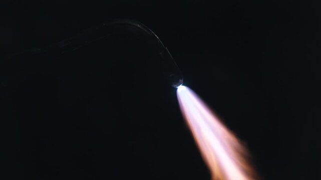 Closeup torch flame cutting metal tip, bluewhite nozzle in dark workshop, jeweler technique showing concentrated heat stream,