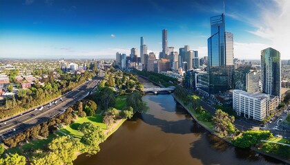 Obraz premium drone vertical shot of the melbourne cityscape with a river and green trees on a sunny day