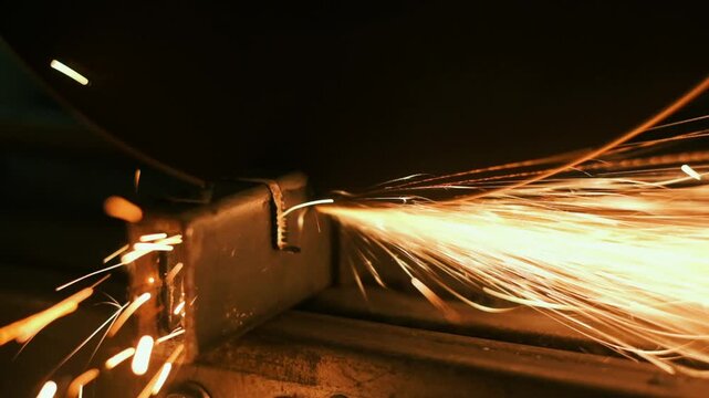 Intense metal grinding sparks fly across dark workshop, cinematic closeup showing abrasive wheel cutting steel, showering bright