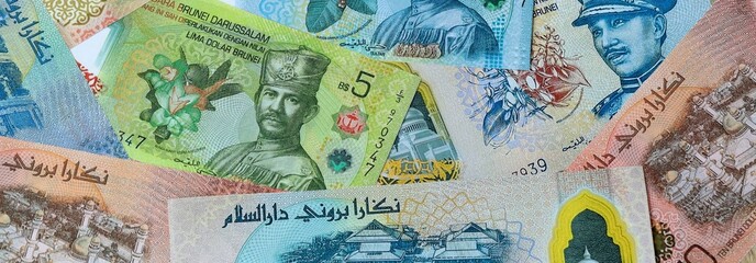 Brunei dollar money banknotes bunch on table. Brunei bills of BND currency close up © Larysa