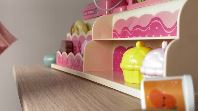 Cute toddler playing with toy grocery store shelf in indoor play center

