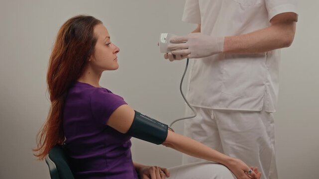 Clinician connects cuff to monitor, patient seated calmly with arm extended, device display prepared for automated reading