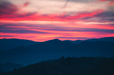 Obraz premium Fantastic sunset over rolling hills creates a breathtaking canvas of vibrant colors in the evening sky. Photo wallpaper.