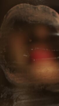 Close-up of woman biting on a screen of transparent plastic wrap and leaving behind lipstick marks