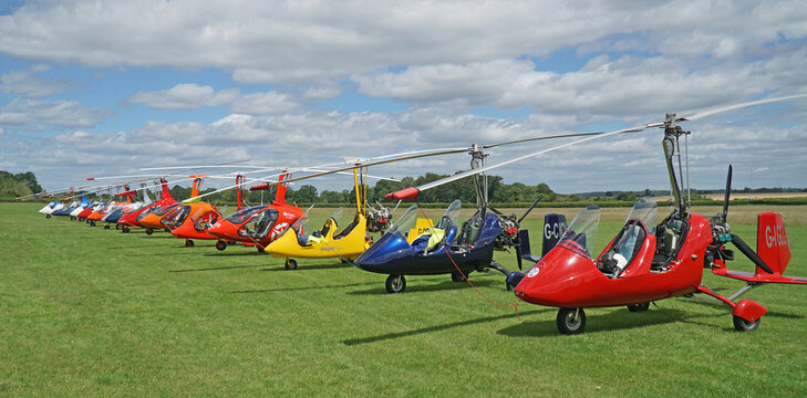 Row of Gyrocopter - Autogyros  parked on grass.
