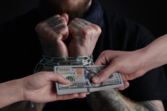 Stop human trafficking. Man with chained hands and traders with money, selective focus