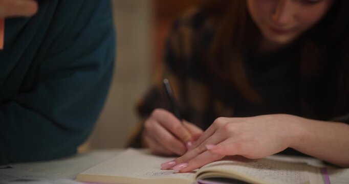 Hands writing in notebook at an indoor table