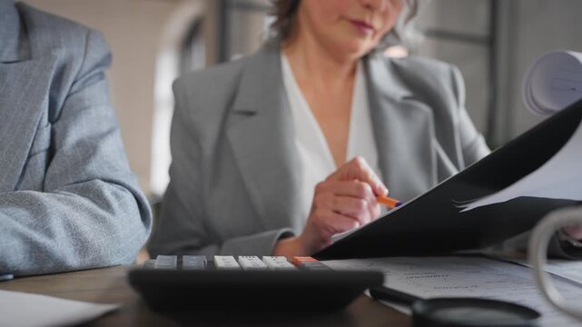 Chief accountant or financial director counting on calculator, closeup view. Senior woman in business meeting in office, board of directors in modern company, decision about investments and finance