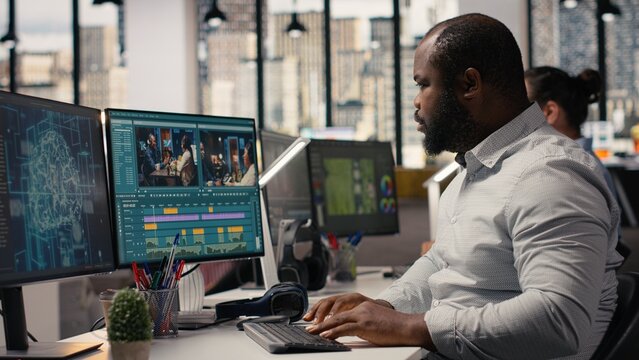 Video editor cutting raw film footage with advanced AI software on PC, working in modern studio office, Creative process shows color grading and motion graphics tools powered by machine learning.