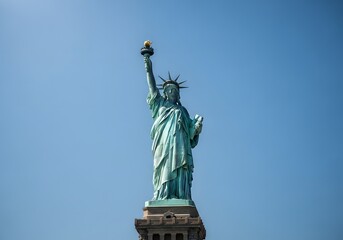 Fototapeta premium The Statue of Liberty stands tall against a vast, clear blue sky, symbolizing freedom and democracy as a world-renowned icon of hope