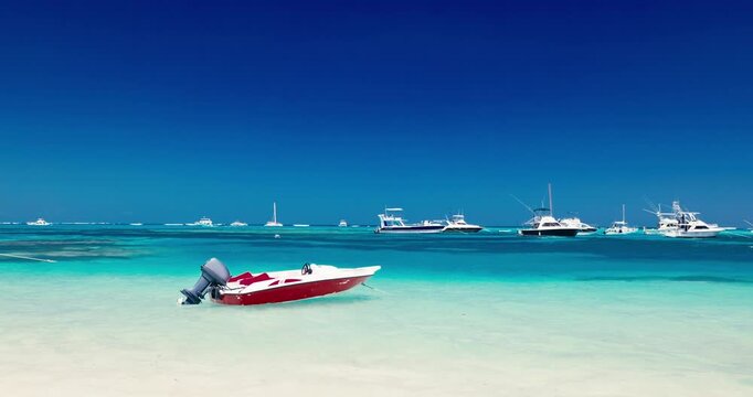 Small motorboat with outboard motor moored on a tropical white sand beach next to turquoise water