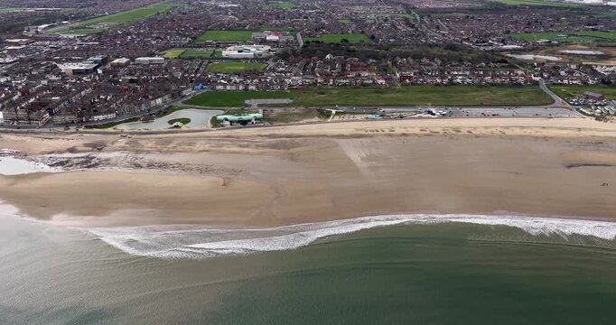 Aerial view of Redcar seafront and sandy beach on the North Yorkshire coast showing coastal housing shoreline waves promenade and urban landscape beside the North Sea under an overcast sky