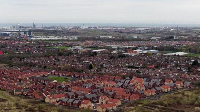 Aerial view of residential housing developments in Redcar North Yorkshire with industrial facilities and port infrastructure in the distance showing urban expansion coastal industry and community life