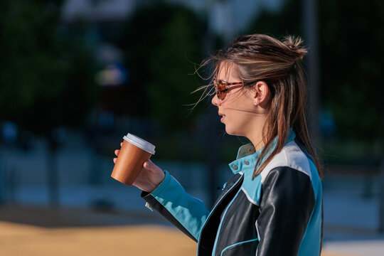 young woman enjoys takeaway coffee while walking in the city