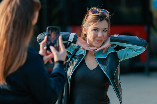 Young woman taking photo of friend with smartphone