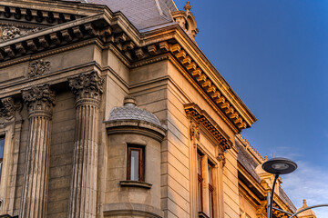 Ornate historic building facade near University Square Bucharest Romania with Corinthian columns and decorative cornice in golden evening light, architectural photography. © Khalil