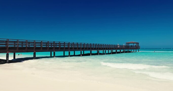 Long wooden pier in turquoise Caribbean sea water. Idyllic tropical beach scenery in Punta Cana, Dominican Republic, paradise island landscape