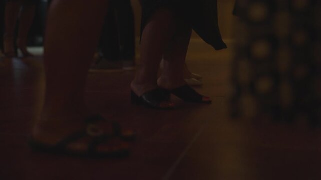 Tight close-up shot of female feet moving across a dance floor, energetic motion, stylish footwear, lively atmosphere, dynamic movement, low-angle perspective, nightlife and dance culture concept.