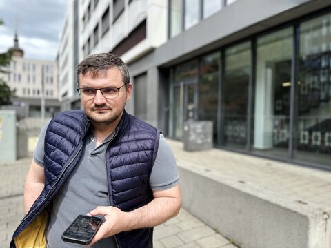Smiling man talking on smartphone in a modern city environment. Authentic urban lifestyle portrait featuring casual menswear, digital communication and contemporary fashion.