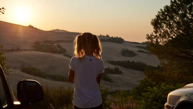Golden sunset light over the rolling countryside of Tuscany, Italy, with trees, dry grass and a rustic wheel creating a peaceful rural landscape.