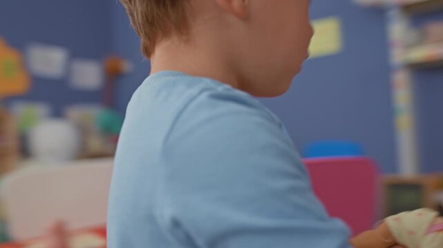 Boy placing plastic toy on red table in building play area while reaching across the surface; concentration learning.