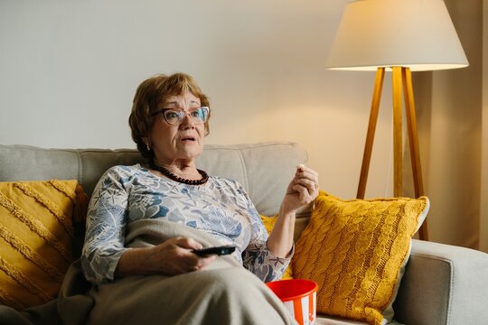 Senior woman watching television with a surprised expression