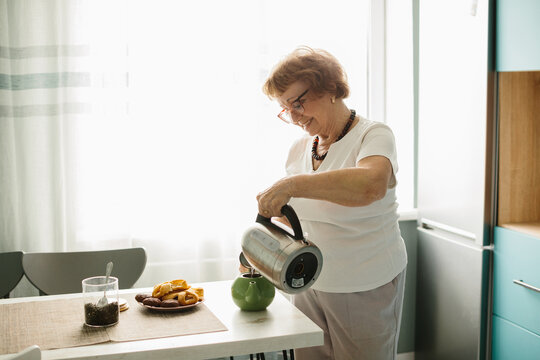 Happy senior woman preparing tea at home