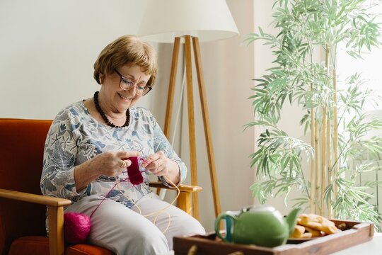 Senior woman knitting at home enjoying leisure time