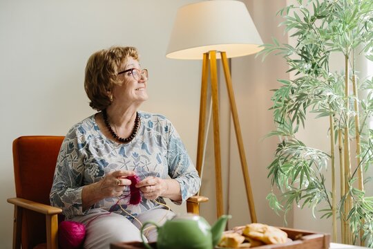 Senior woman knitting, enjoying leisure time at home