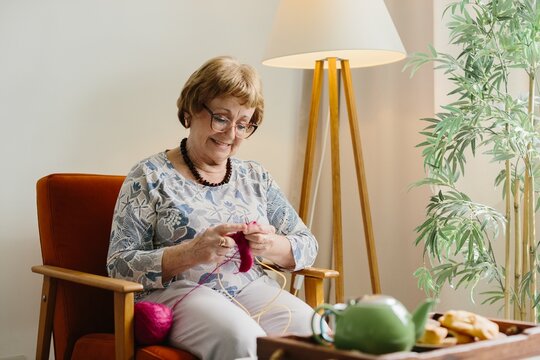 Senior woman smiling enjoying knitting hobby at home