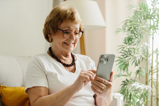Senior woman smiling enjoying mobile phone technology at home