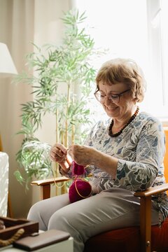 Senior woman knitting at home for hobby and relaxation