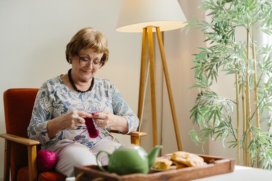Senior woman knitting, enjoying leisure time at home