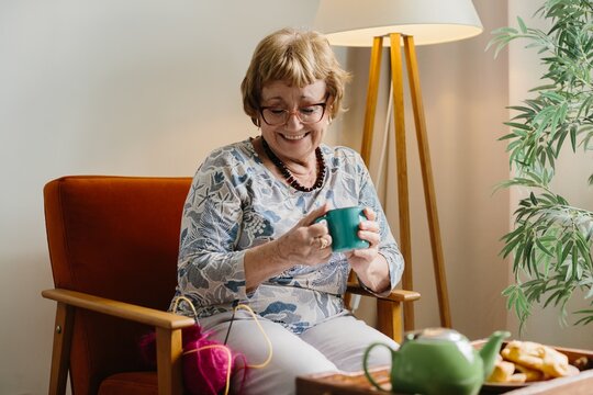 Senior woman smiling enjoying warm drink at home
