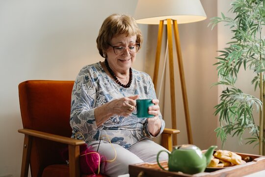 Senior woman relaxing at home enjoying tea and treats