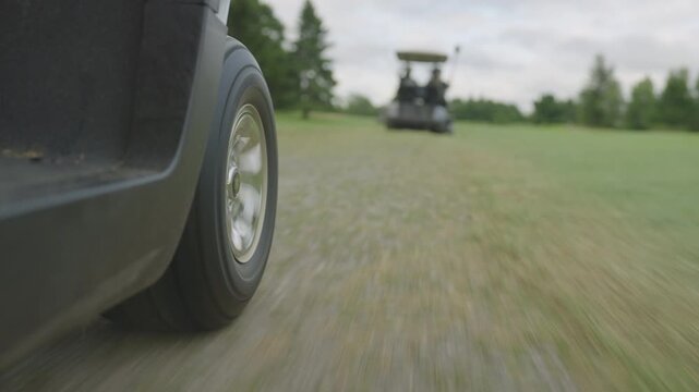 Low POV shot driving down the fairway of a golf course in a golf cart, camera positioned tight on one wheel near the grass, dynamic motion through manicured greens, cinematic outdoor sports scene