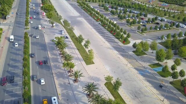 Aerial drone shot featuring a panning view over the busy Turgut Ozal coastal boulevard and the adjacent Maltepe Orhangazi City Park in Istanbul.