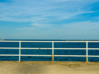 Fototapeta premium View of the ocean from a pier with a clear sky and boats on the water during the day