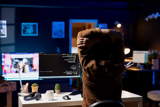 Programmer doing software quality assurance, stretching arms behind back after reading source code, feeling fatigued. IT expert taking break from work to relax muscles after inspecting coding.