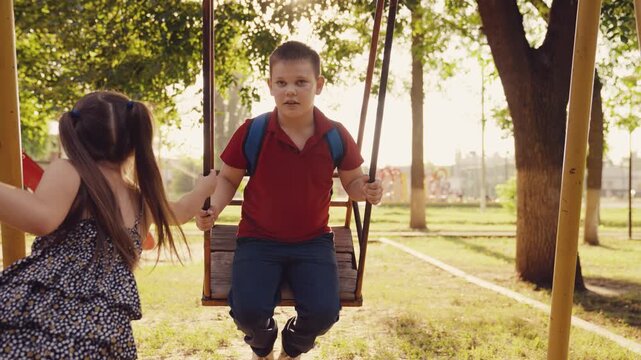child girl rides swing, happy childhood concept, happy children dream, happy family, child play playground, boy friend helps little girl ride swing, happy smile boy girl face, team work playground,
