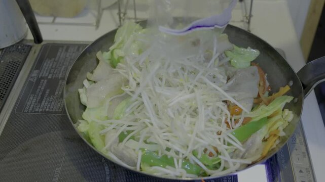 大型直径32cmの鉄フライパンを用い、肉野菜炒めの調理で、最後にもやしを入れ、かき混ぜるシーン　37秒