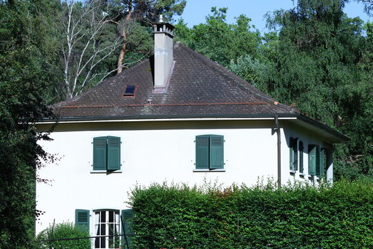Maison traditionnelle blanche aux volets verts entour&eacute;e de v&eacute;g&eacute;tation