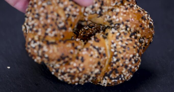 Braided simite with sesame seeds, freshly baked simite with a crispy crust is located on a black matte slate on the left side of the frame.