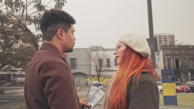 Young man inviting a redhead woman to the cinema with tickets