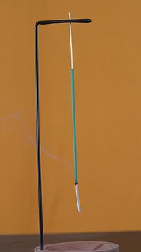 A green incense stick burning upside down.