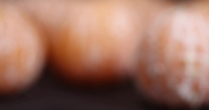focus on a whole juicy orange-colored peeled tangerine on a black slate table, a ripe orange small mandarin without a peel on a black slate board