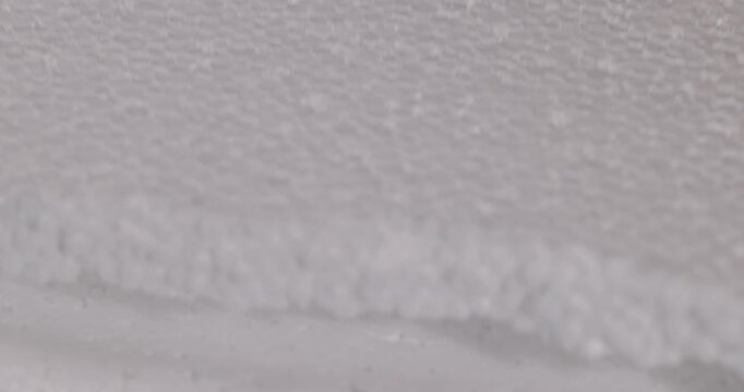 White foam in two layers, porous foam with a rough fracture edge is positioned diagonally across the frame, creating a three-dimensional surface texture.