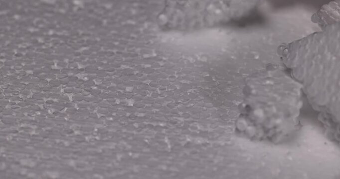 White foam granules on a sheet, a scattering of small foam balls lies next to large fragments of porous packaging material.