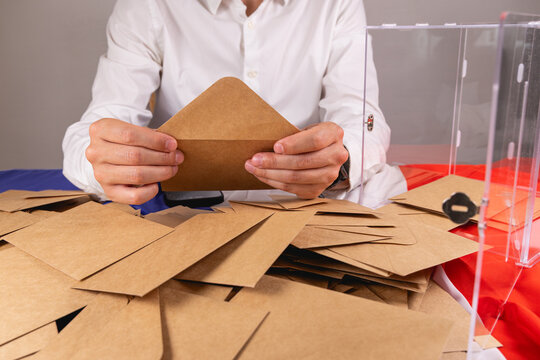 Une personne en train de d&eacute;pouiller les bulletins de vote dans les enveloppes, lors des &eacute;lections. &Agrave; c&ocirc;t&eacute;, une urne ouverte. Sur la table, le drapeau de la France.