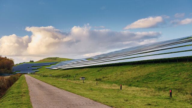 Wijster, Netherlands - 27 October 2024: View of solar panels installed on the grassy slopes of the VAM-berg landfill hill under a blue sky with white clouds.
